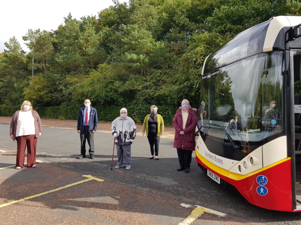 Community transport group members, standing by a bus